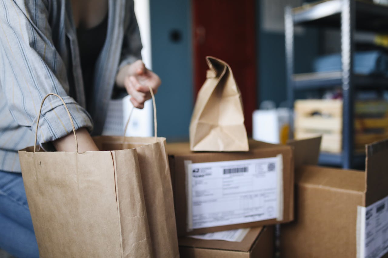 Woman sorting parcels and paper bags in a home setting, showcasing online shopping and delivery.